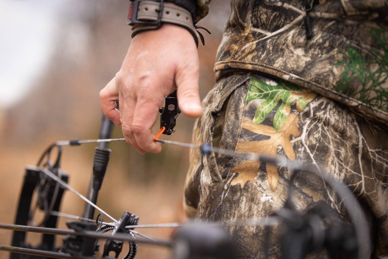 Bowhunter carrying compound bow with Scott Archery release aid in the field