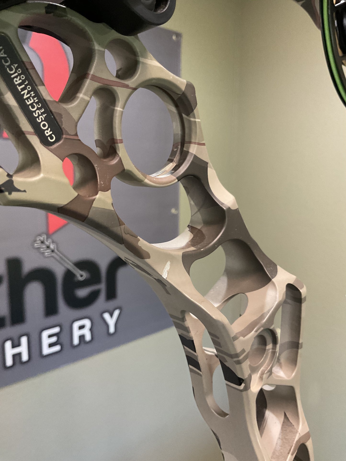 Close up image of a used Mathews Archery compound bow riser in camo color. 