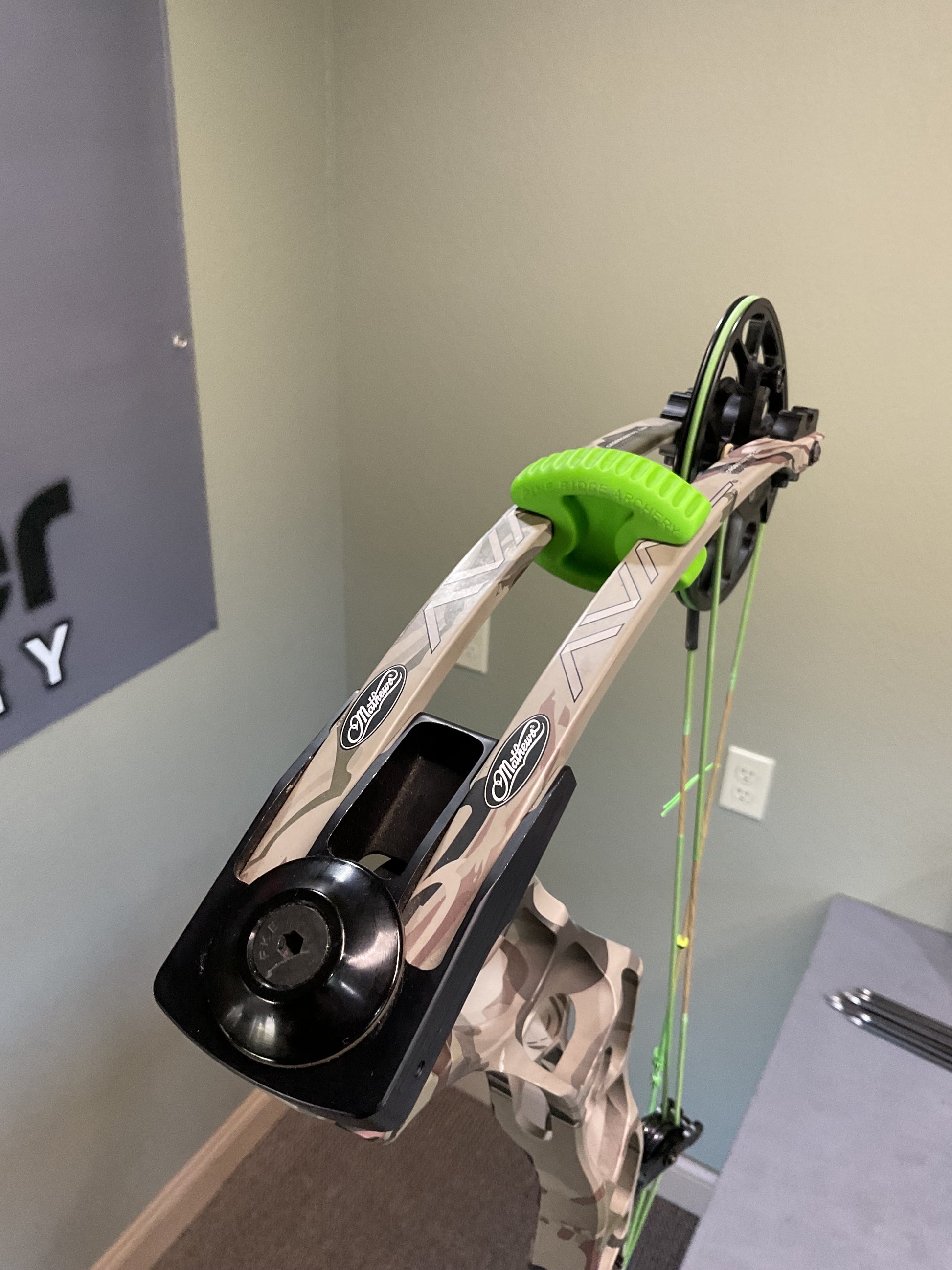 Limbs of a Mathews Archery compound bow in camo color and green limb dampeners. 